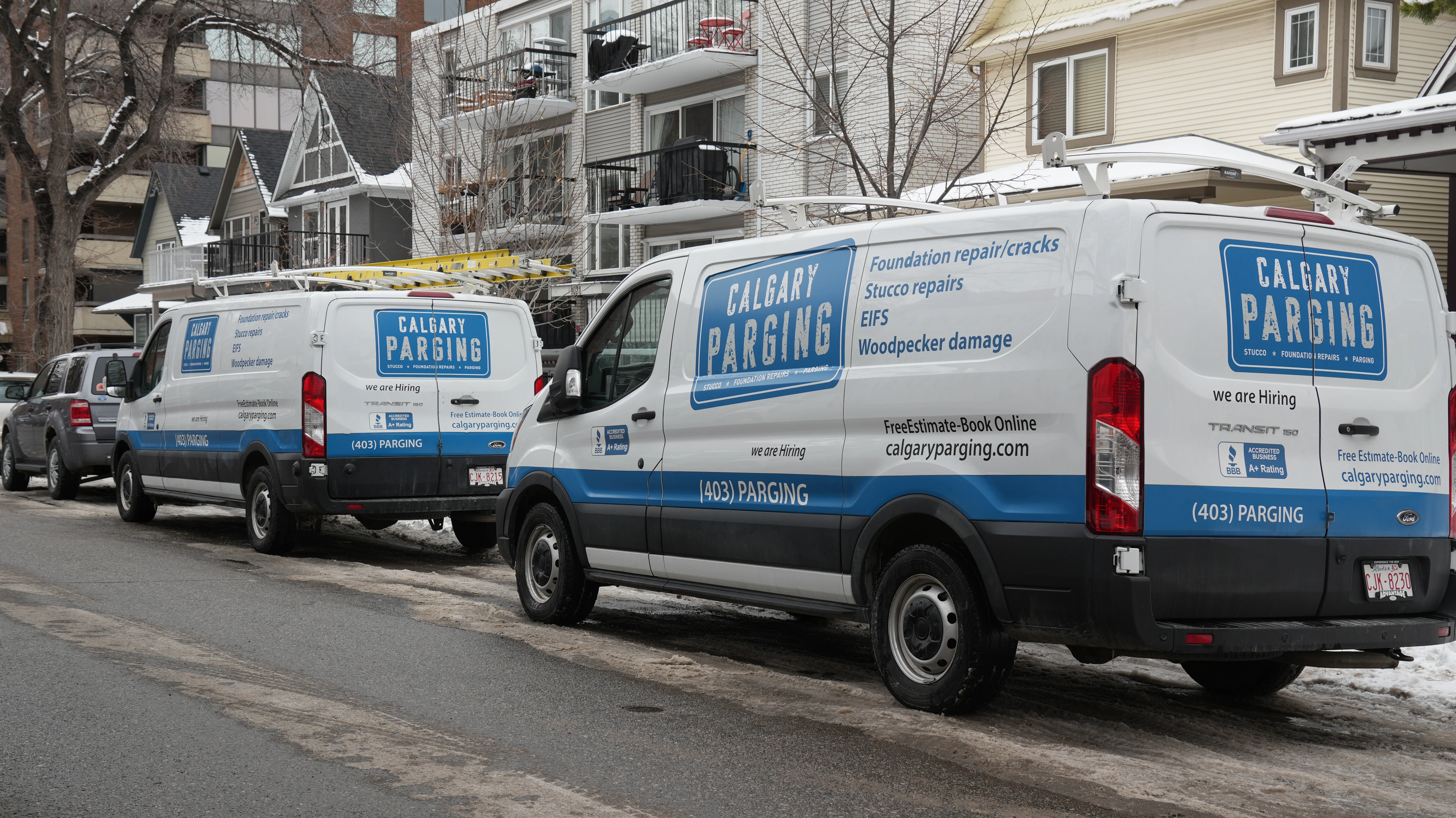 Two Calgary Parging vans parked on-site while the crew repairs foundation parging in Calgary, AB