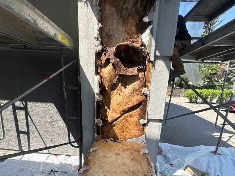 Water damaged stucco on an arched portico before restoration, showing failed finish and staining