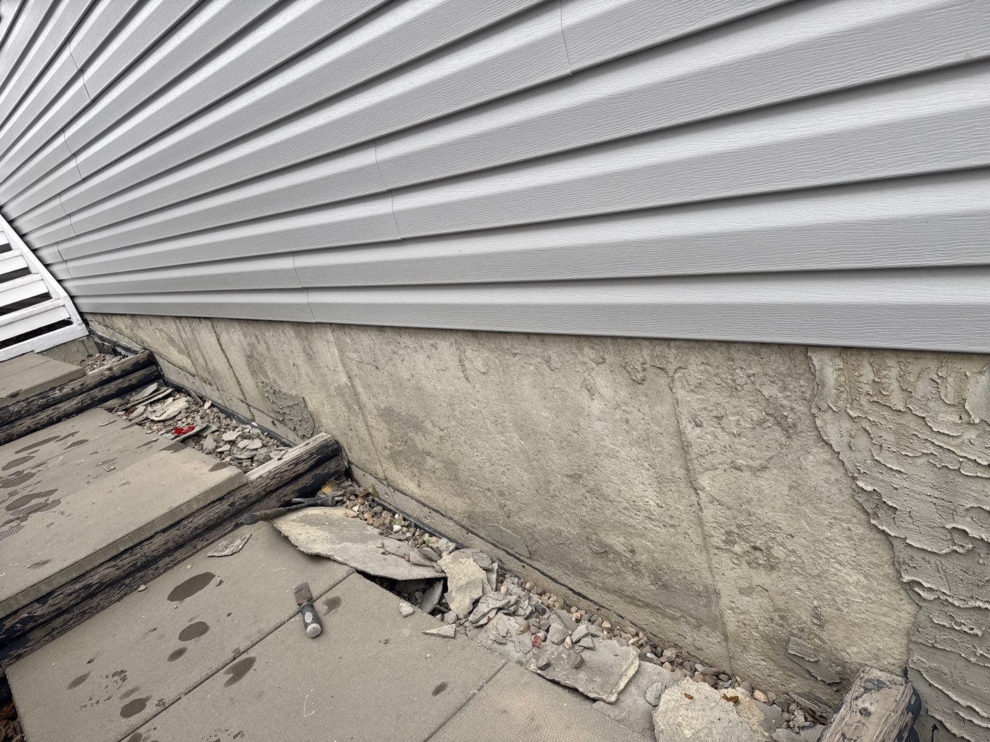 Fallen, deteriorated parging on a Calgary foundation before repair