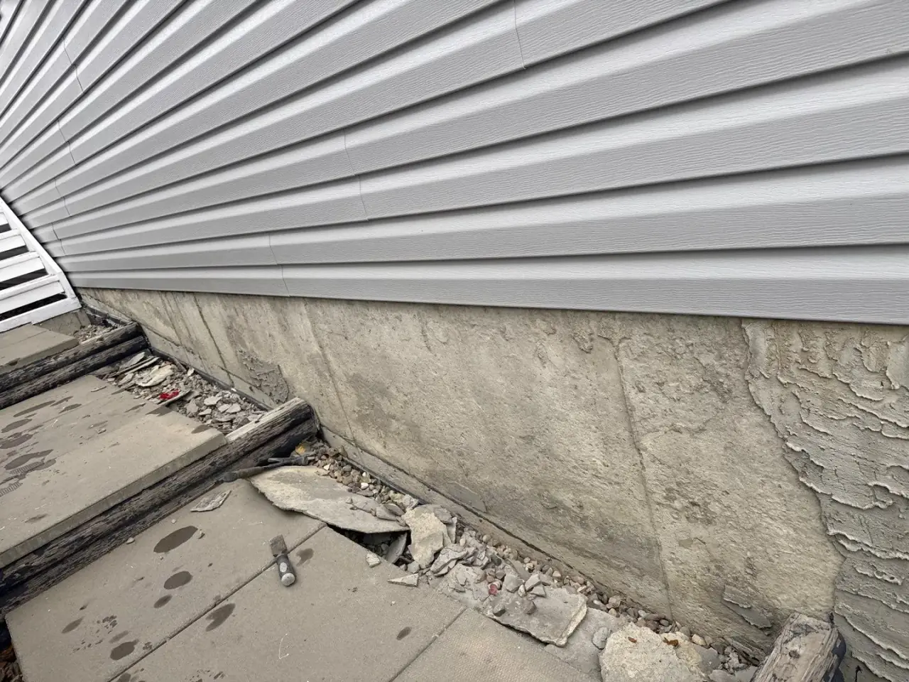 Fallen, deteriorated parging on a Calgary foundation before repair