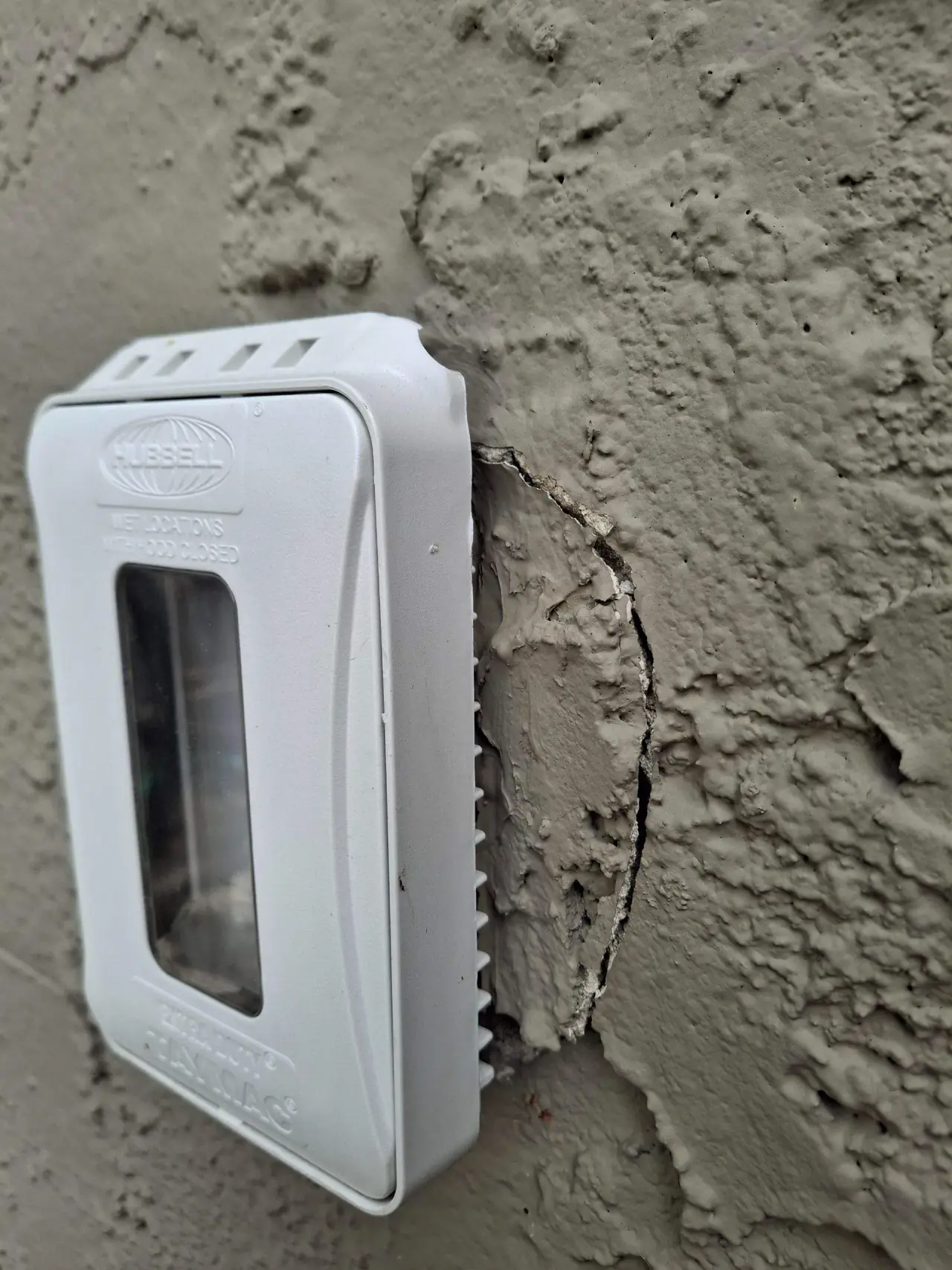 Cracked stucco around an outdoor outlet before repair