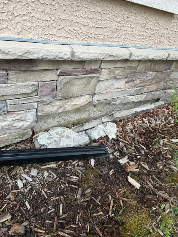 Fallen natural stone foundation before masonry repair in Calgary