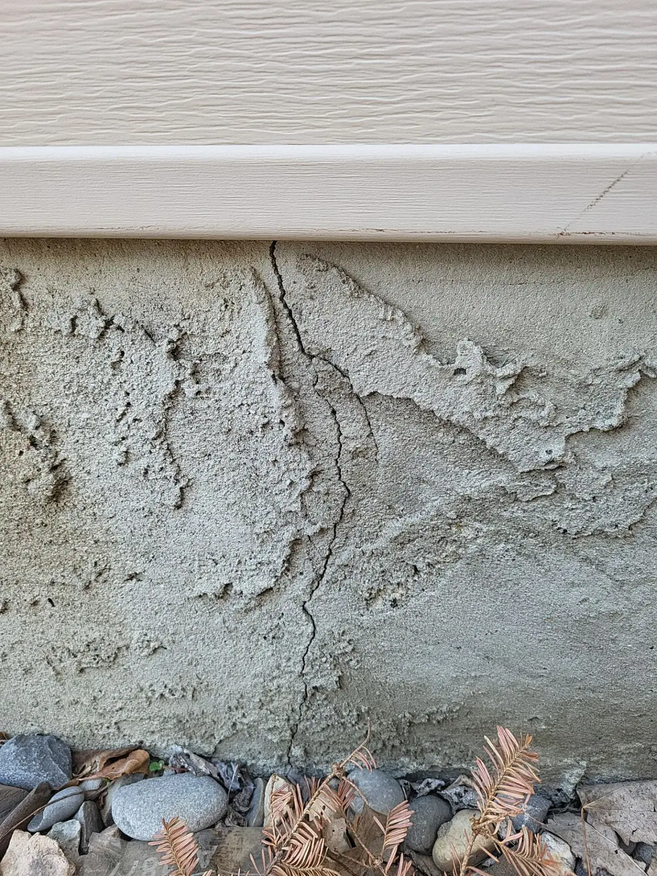 Vertical crack in old parging on a Calgary home
