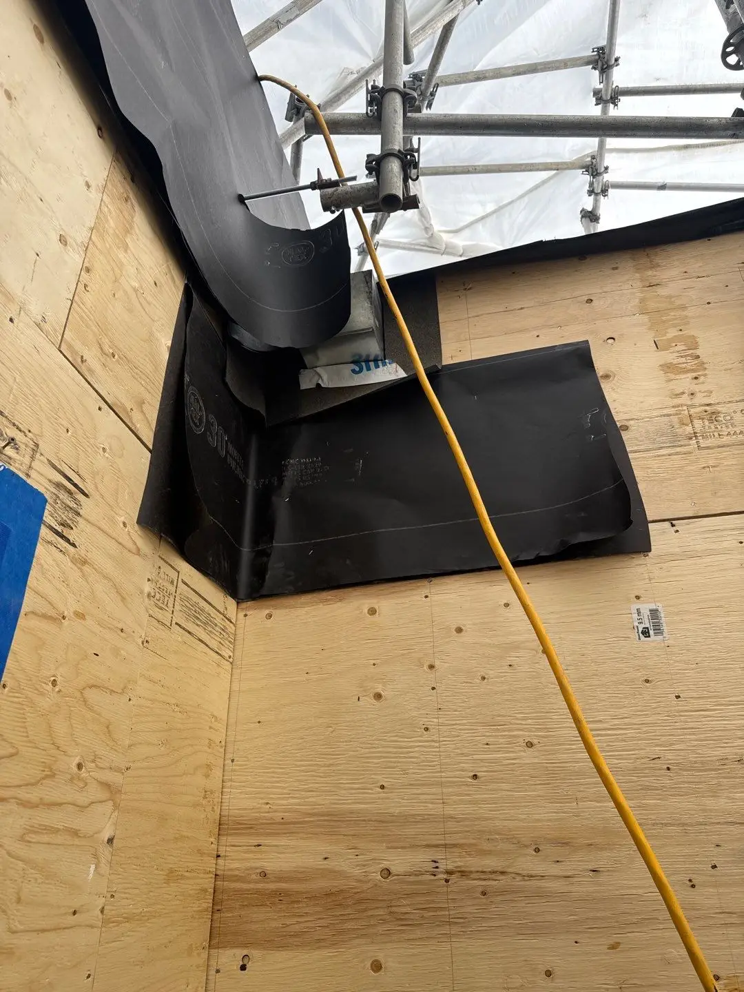 New 9.5mm plywood sheathing installed with 30 minute building paper starter patches shingle-lapped around a gas line penetration