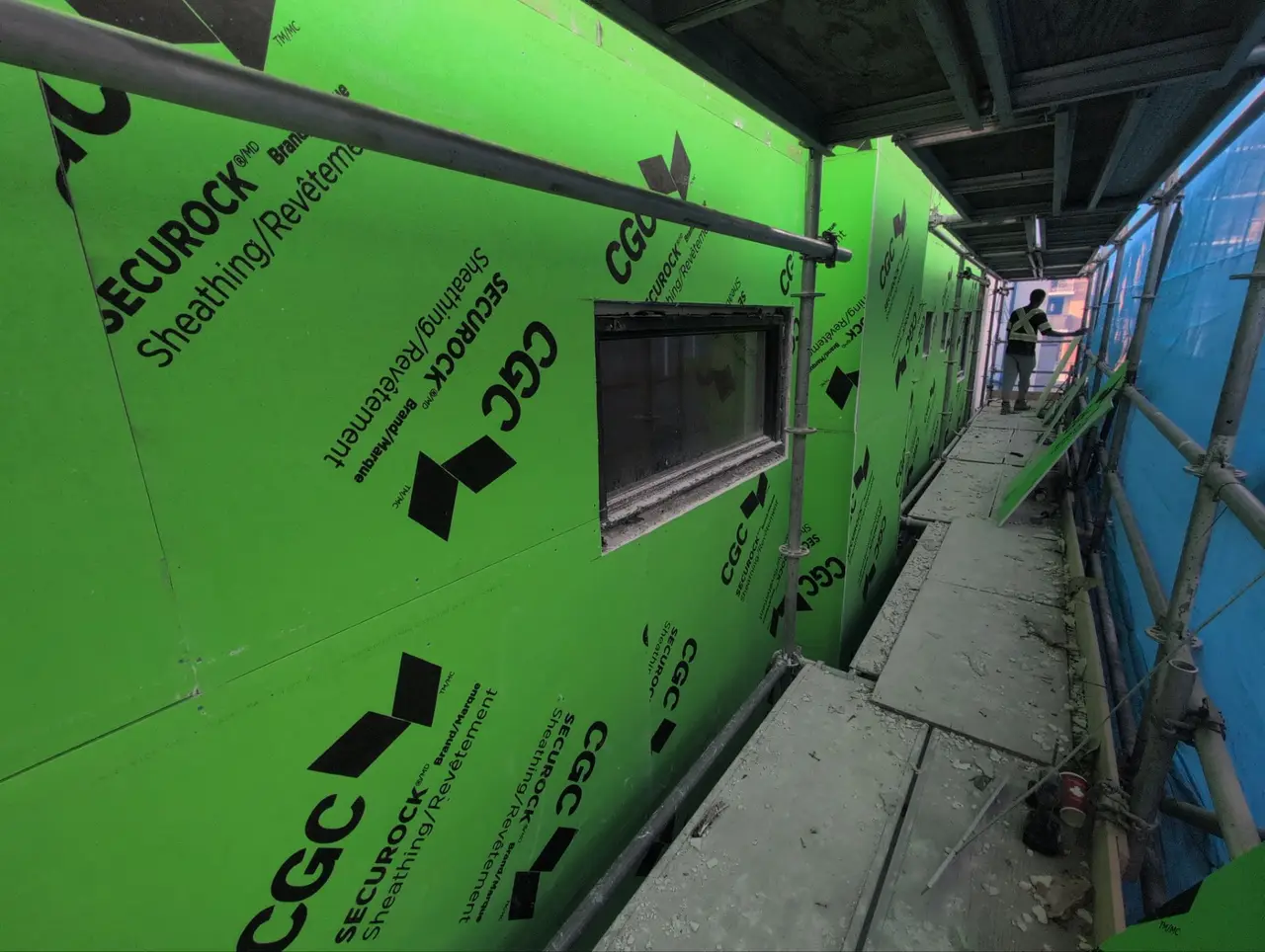 Green CGC Securock exterior fire-rated sheathing installed on a Calgary party-wall elevation with scaffold access