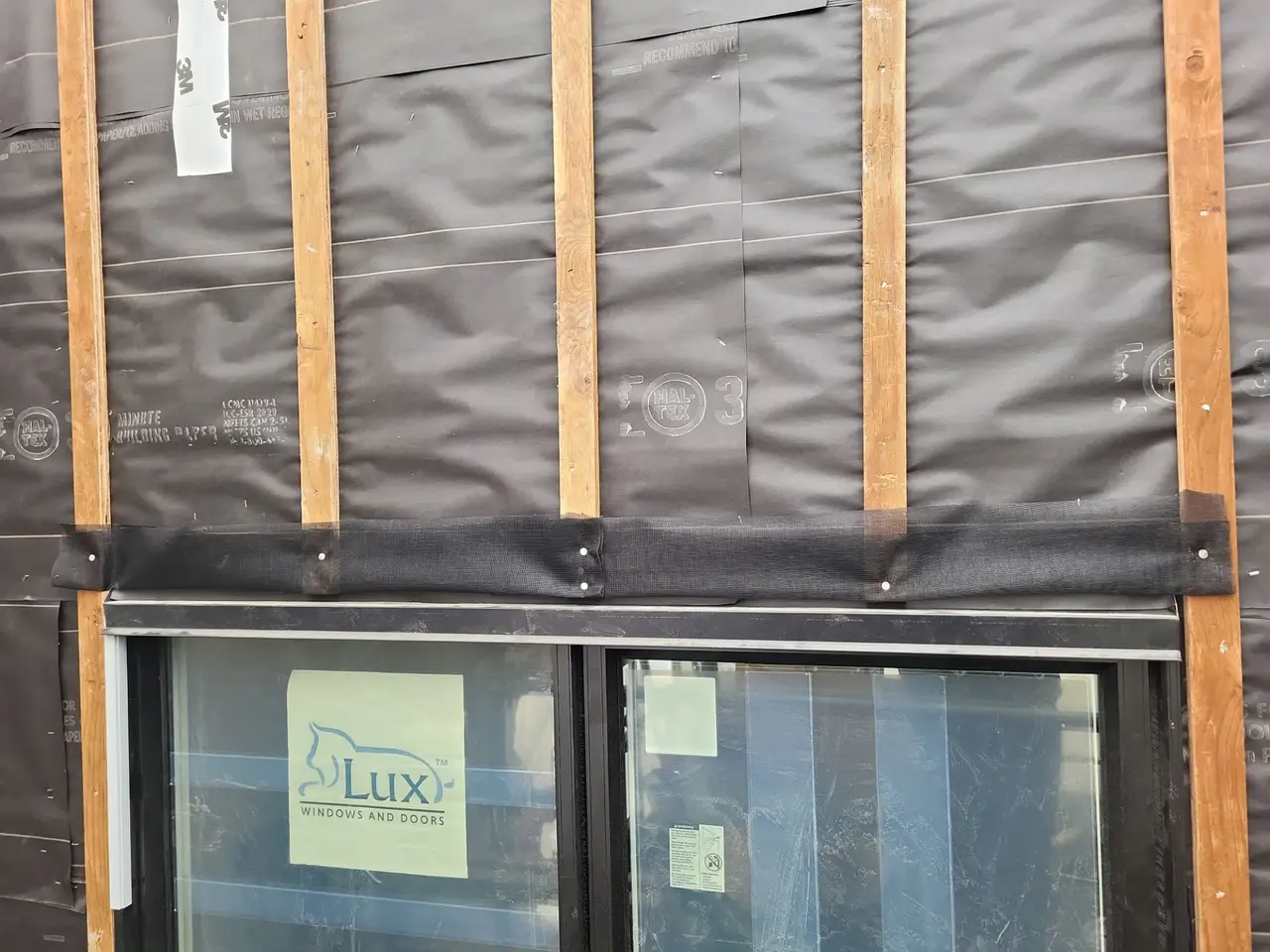 Pressure treated rainscreen strapping and head flashing above a new window, showing the drained cavity carried across the opening
