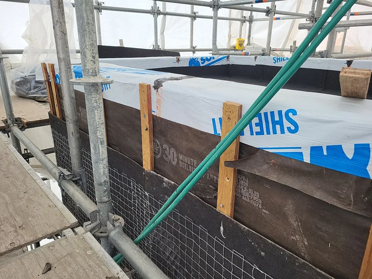 Wire lath over rainscreen strapping tying into 30 minute building paper with Soprema membrane carried over the parapet wall
