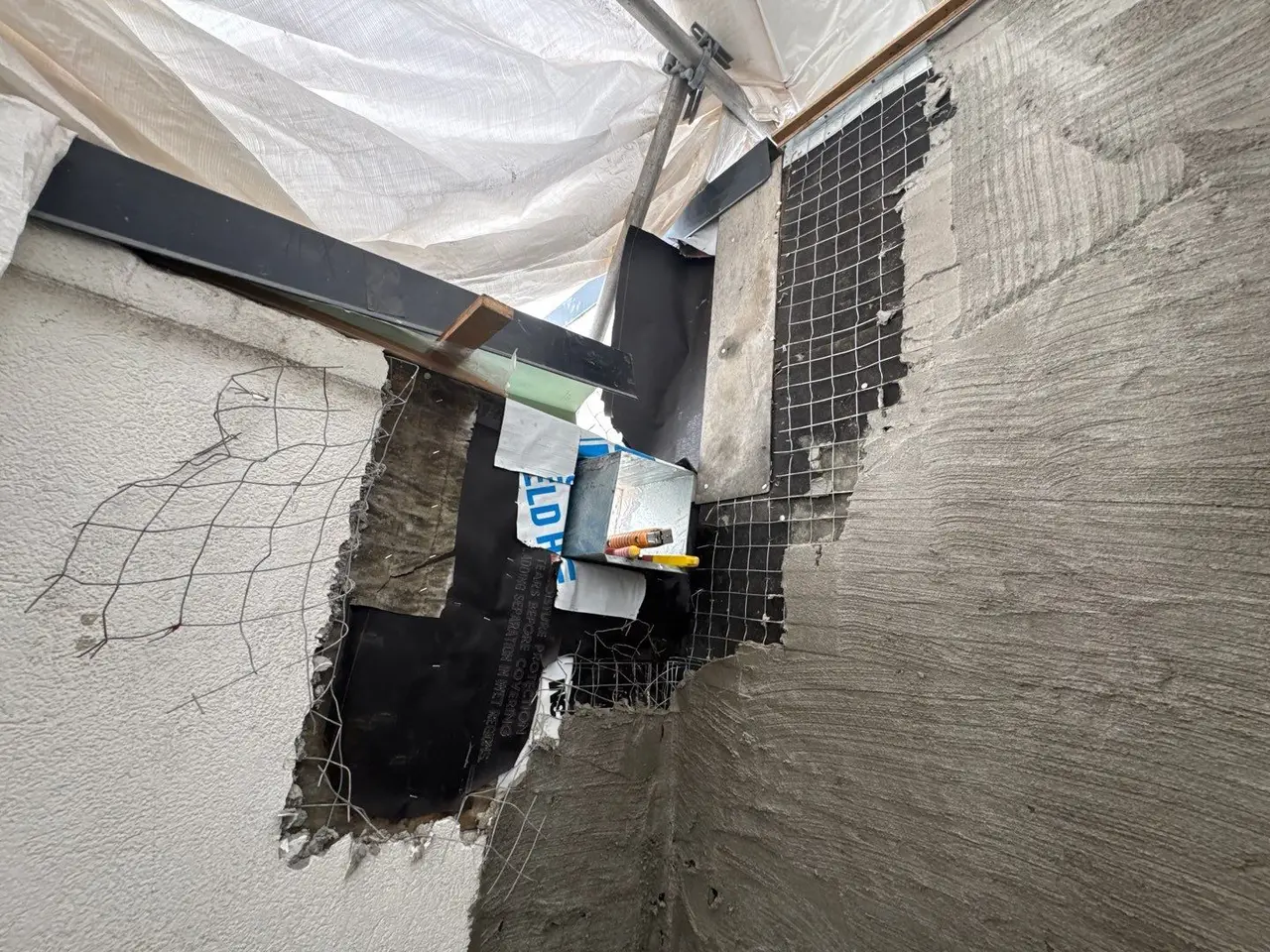 Portland cement scratch coat applied over wire lath and horizontally scratched, with an opening held for the scupper installation