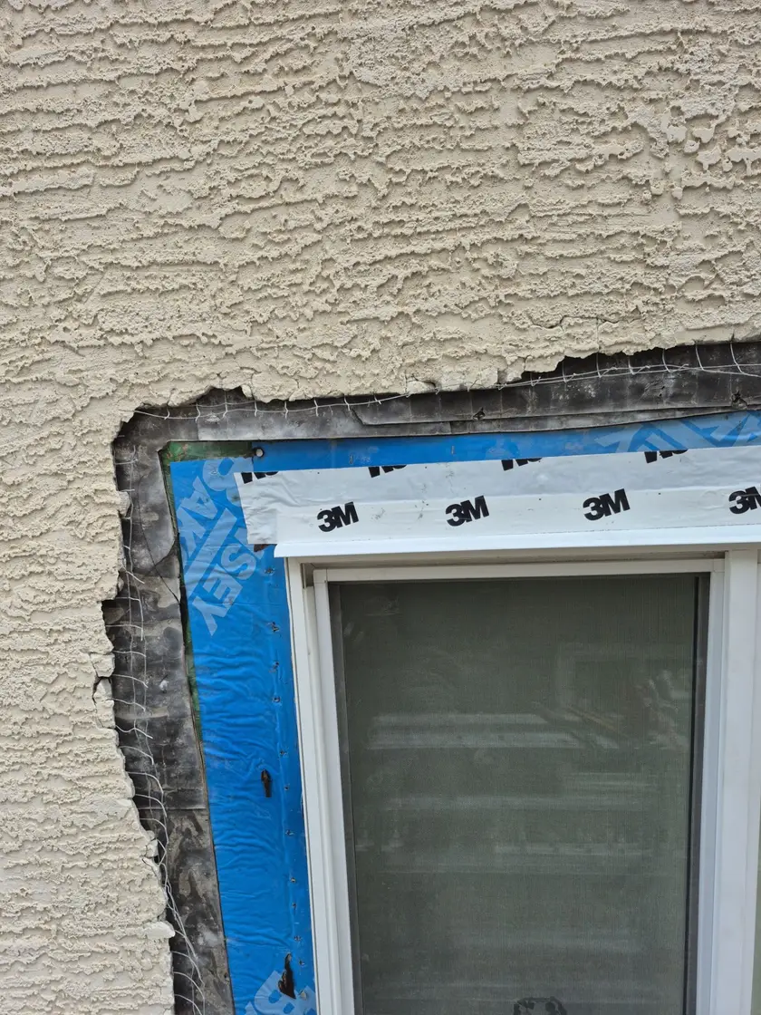 Blue self-adhered membrane over a window nail flange with flashing tape shingle-lapped across the head