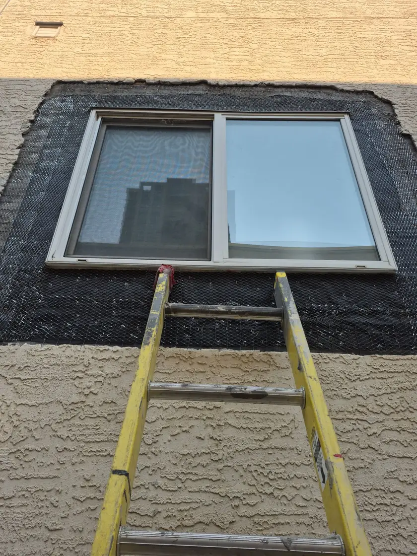 New wire lath installed around a window opening and lapped over the existing wire mesh at the patch perimeter
