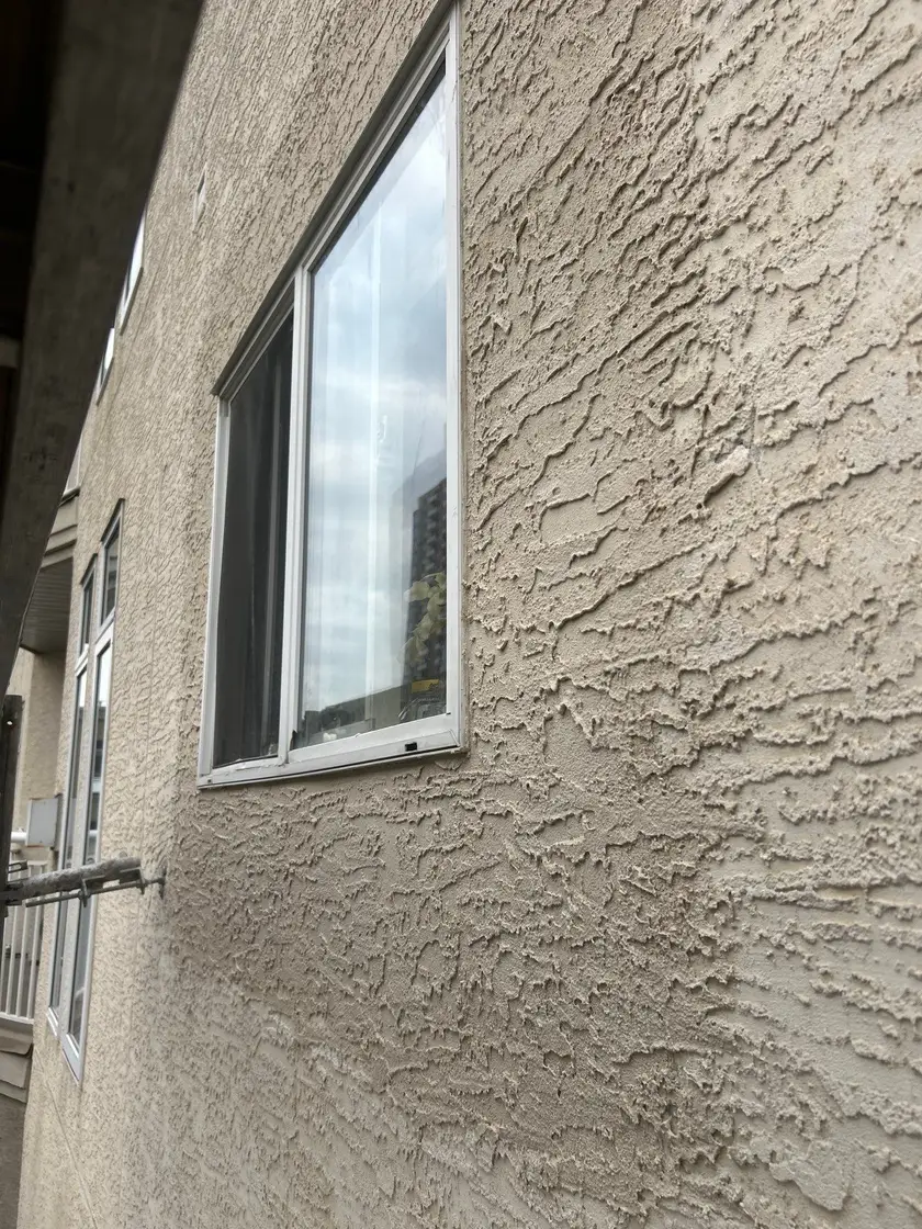 Finished textured stucco around a window, colour and texture matched to the surrounding wall with no visible patch line