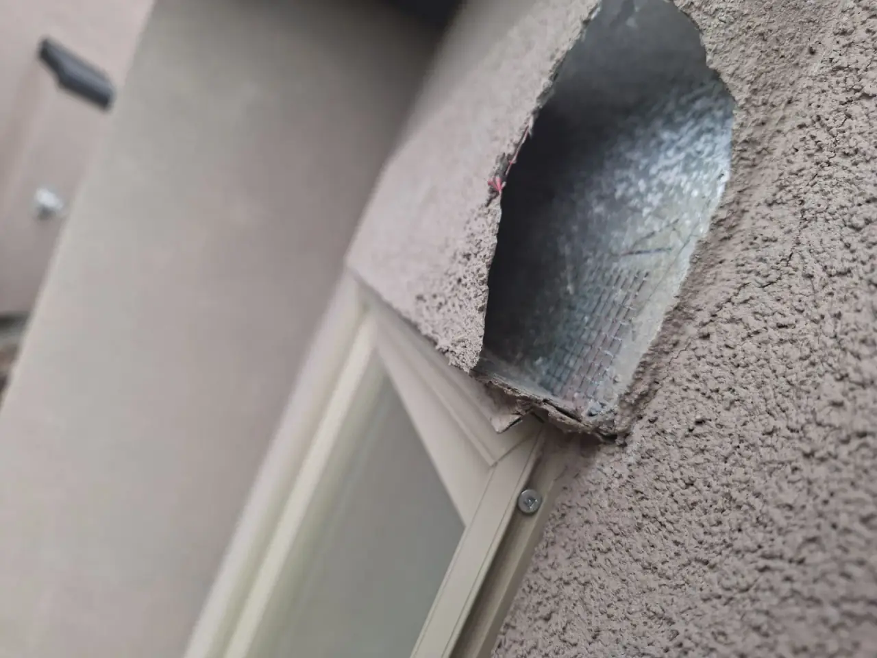 EIFS stucco above window batten damaged by woodpeckers